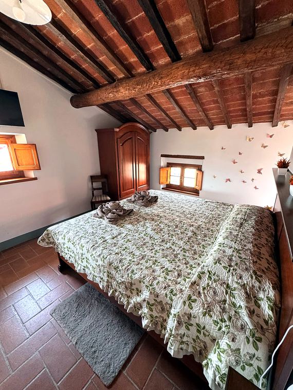 Camera Marrone: letto matrimoniale con copriletto tortora sotto il soffitto a travi