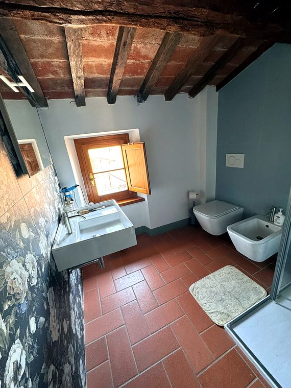 Bagno Camera Marrone: Sanitari sospesi e finestra sui tetti