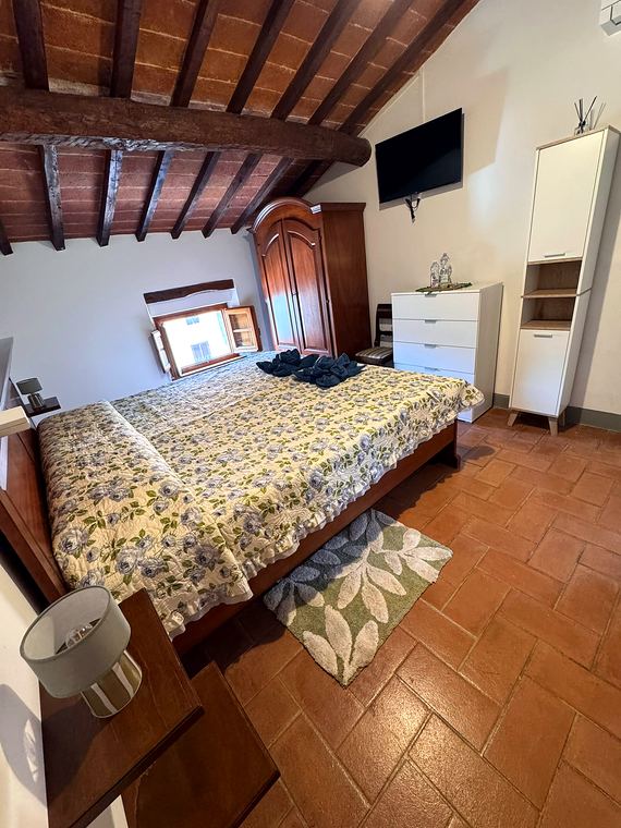 Camera Verde: letto matrimoniale sotto il soffitto a travi, con TV e arredi bianchi